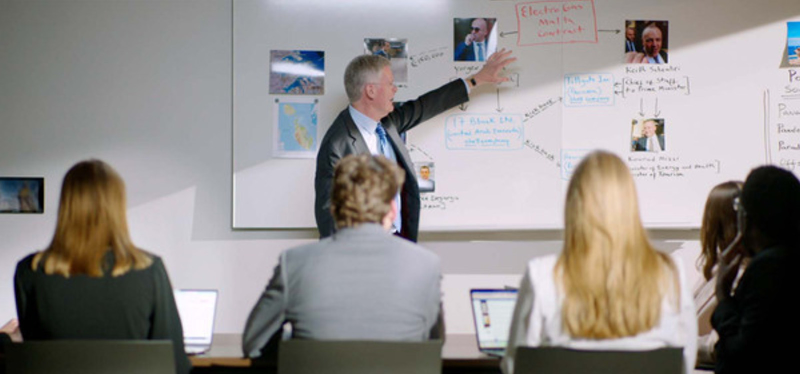 Thomas Kellenberg stands at a white board teaching a group of students