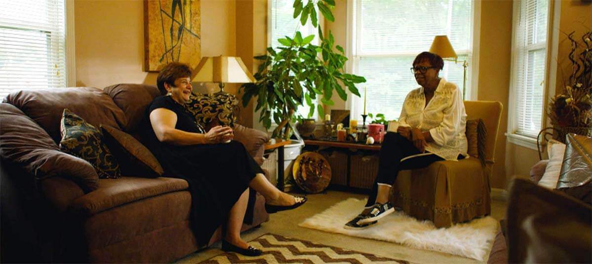Judith Fox and a Law Clinic client sit in a home.