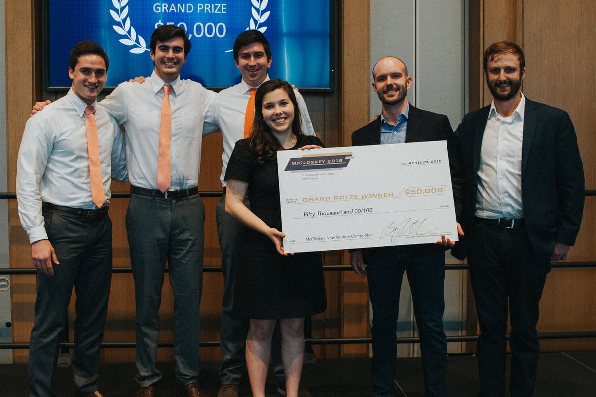 Six students post with a giant check for $50,000.