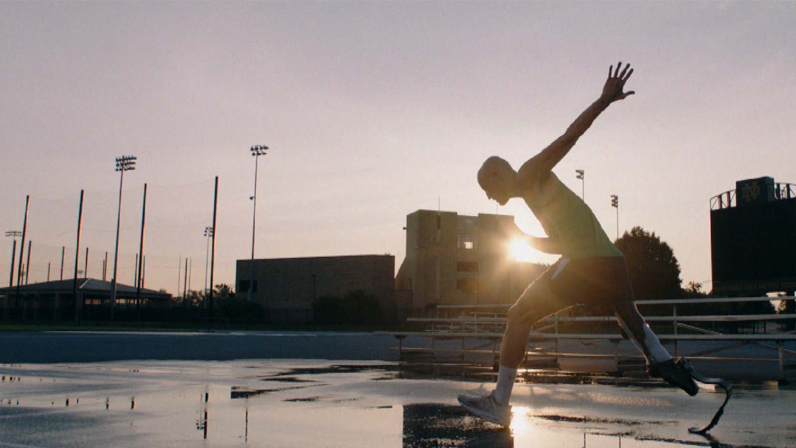 A man with a prosthetic leg preps to do a high jump on a track at sunset.