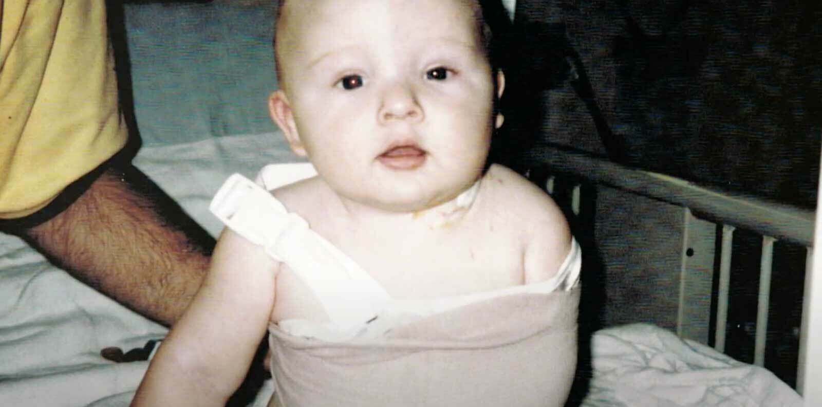 Home photo of a baby wearing an arm sling.
