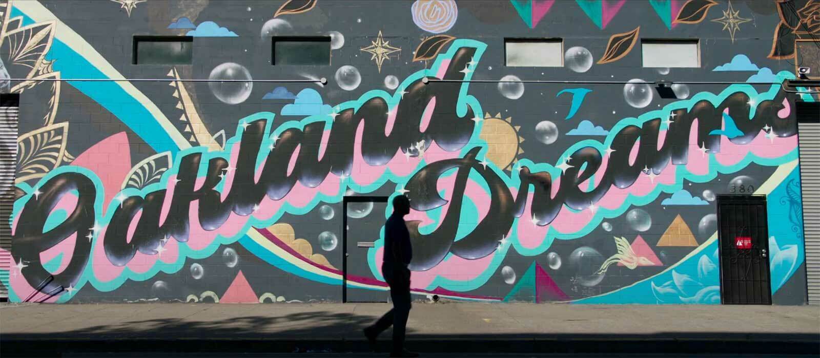 Bubbly and colorful graffiti reads 'Oakland Dreams' on an exterior wall.