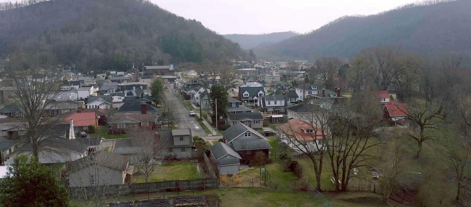 A small neighborhood of homes tucked between two tree covered mountains.