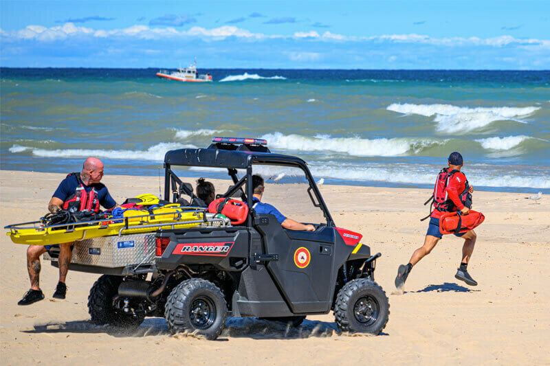 First responders riding in a Utility Terrain Vehicle on the beach in a training exercise. 