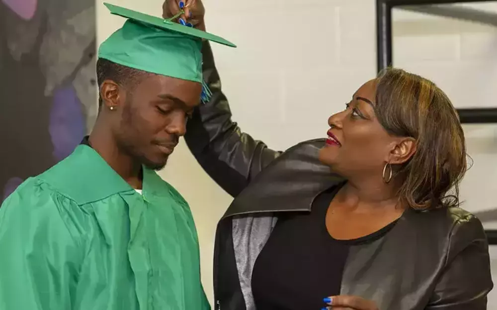 Woman adjusts cap of graduate before ceremony.