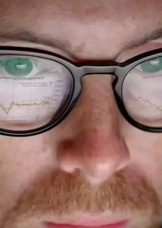 Close-up view of Patrick Turner's face with reflection of a computer screen in his glasses.