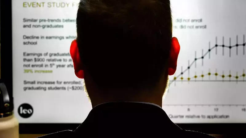 A view from behind Patrick Turner as he views a lit computer screen with graphs and text displayed.