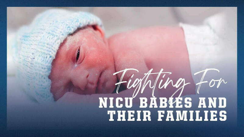 A newborn NICU baby laying on it&#39;s stomach wearing a knit cap.