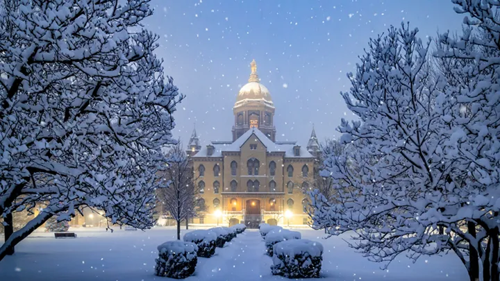 A snow covered Main Building at the University of Notre Dame with snowflakes gently falling around it.