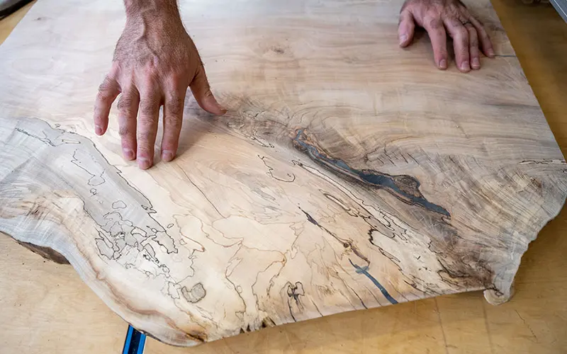 A close up of hands on a piece of wood with really defined wood grain.